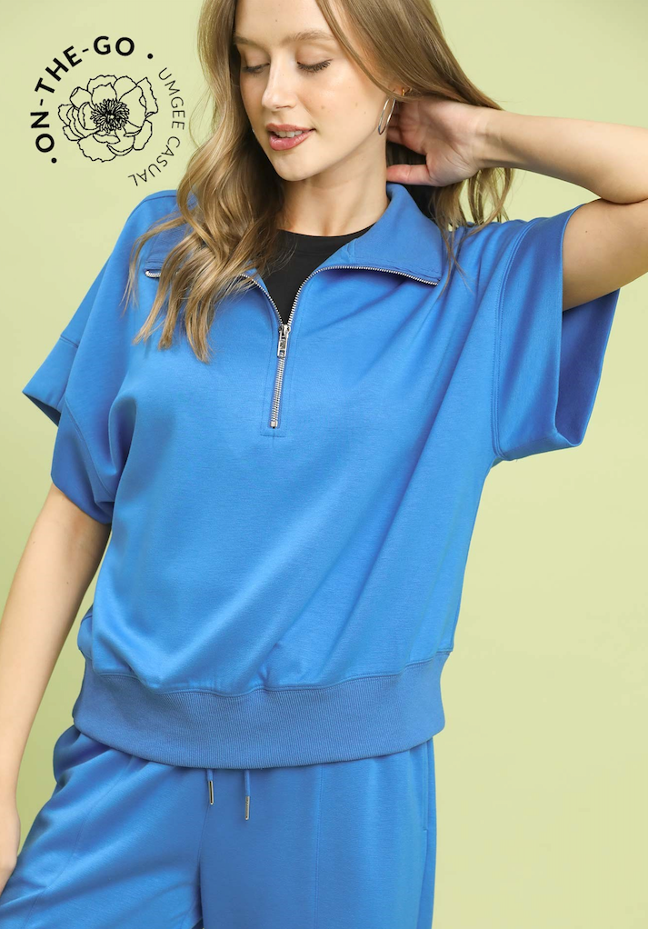 Woman wearing a blue outfit with a green background, featuring the 'On-The-Go' brand.