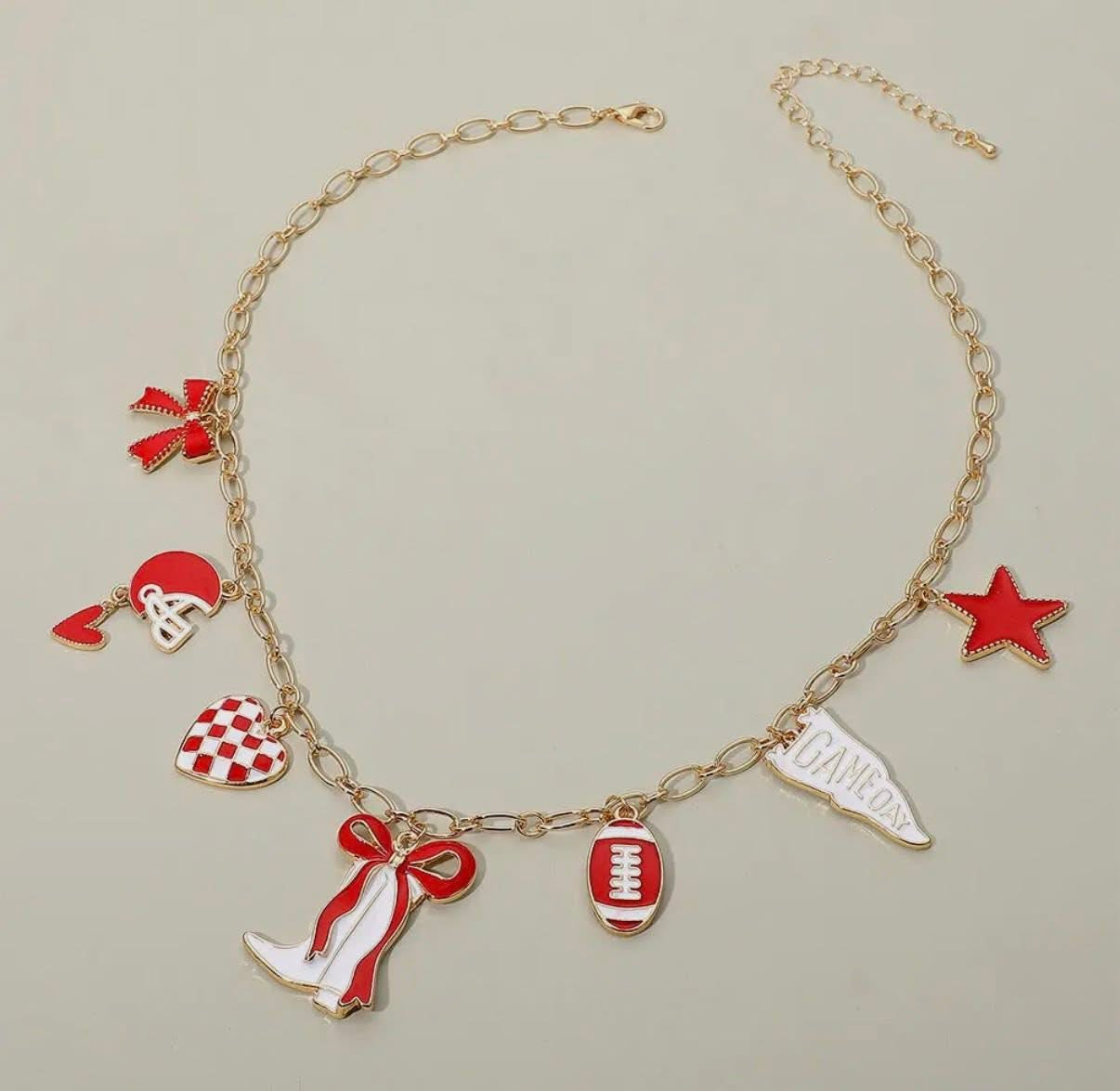 Gold bracelet with red and white charms on a beige background