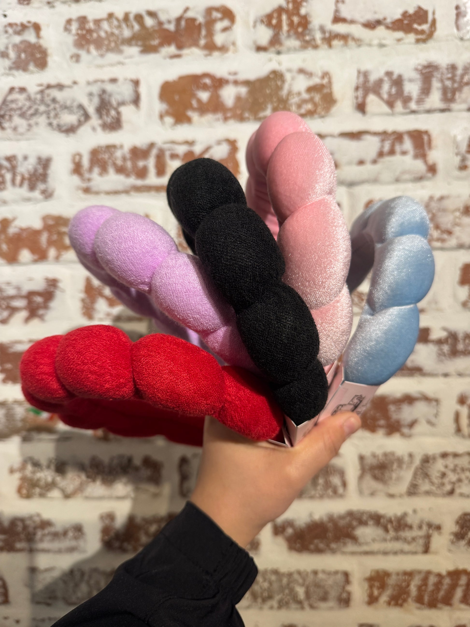 Hand holding colorful hair ties against a textured wall background