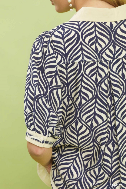 Person wearing a navy and white patterned shirt against a light green background