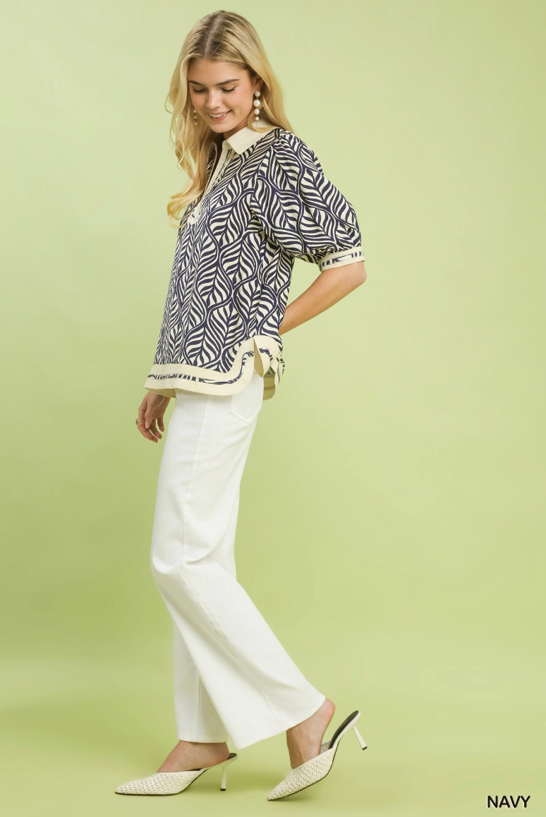 Woman wearing a patterned top and white pants on a light green background