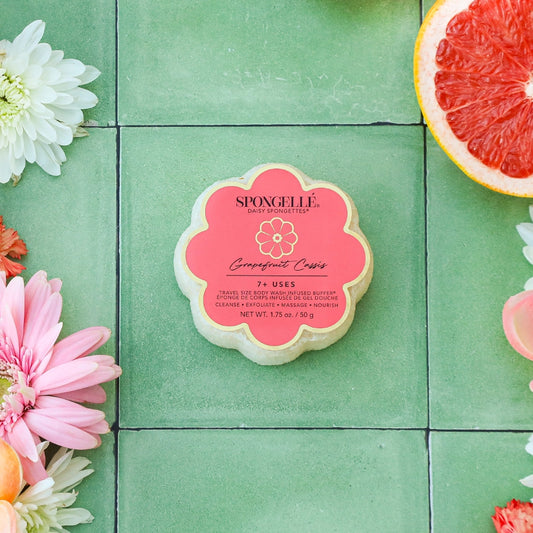 Spongee product on a green tiled background with flowers and a grapefruit slice.