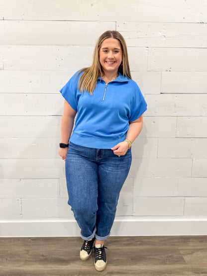 Woman wearing a blue outfit with a white background on a brown floor