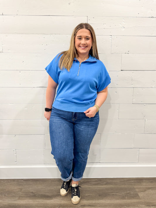 Woman wearing a blue outfit with a white background on a brown floor