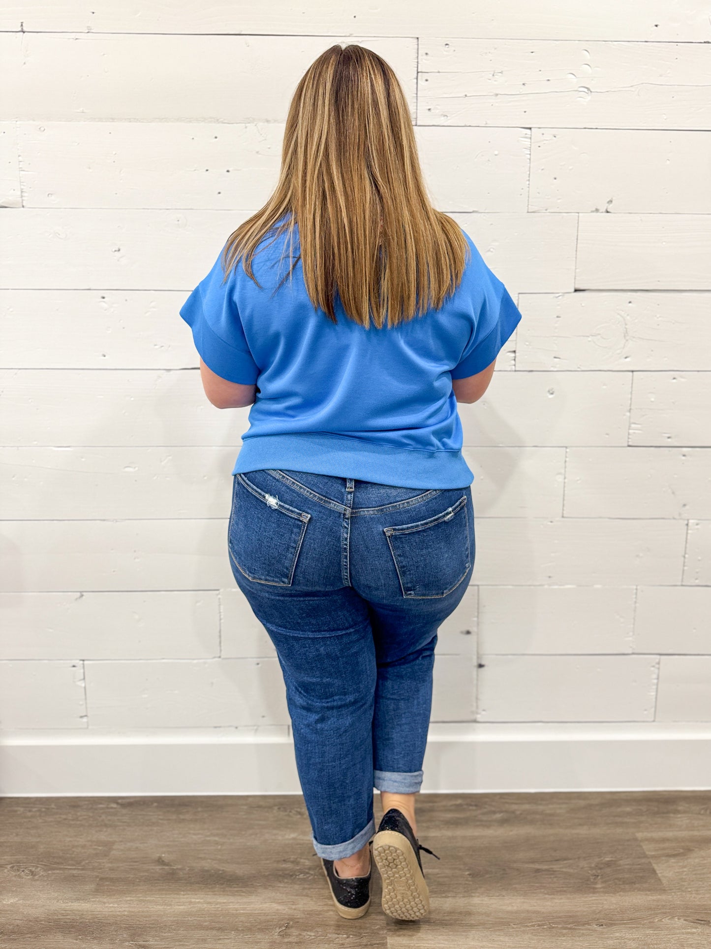 Woman wearing a blue outfit with a white background on a brown floor