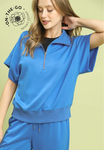 Woman wearing a blue outfit with a visible brand logo on a light green background