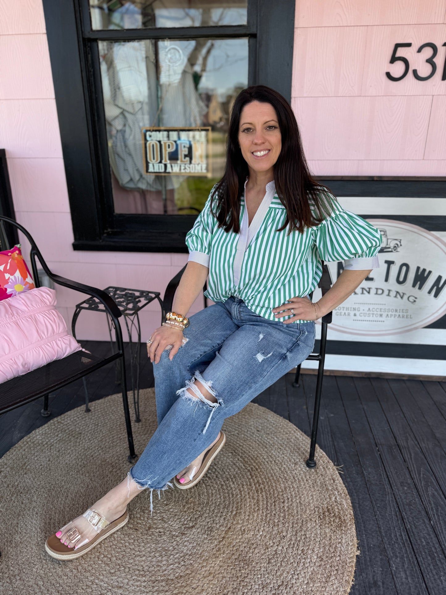 Woman sitting on a chair in front of a building with a sign that reads '531'.