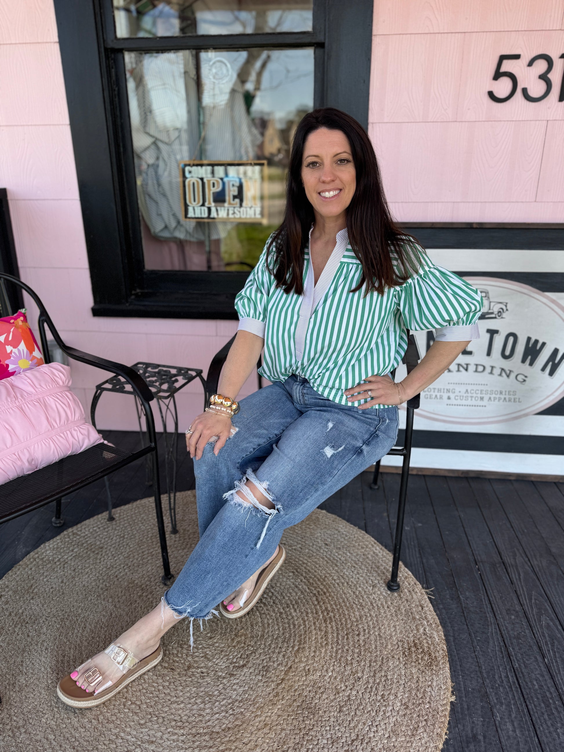 Woman sitting on a chair in front of a building with a sign that reads '531'.