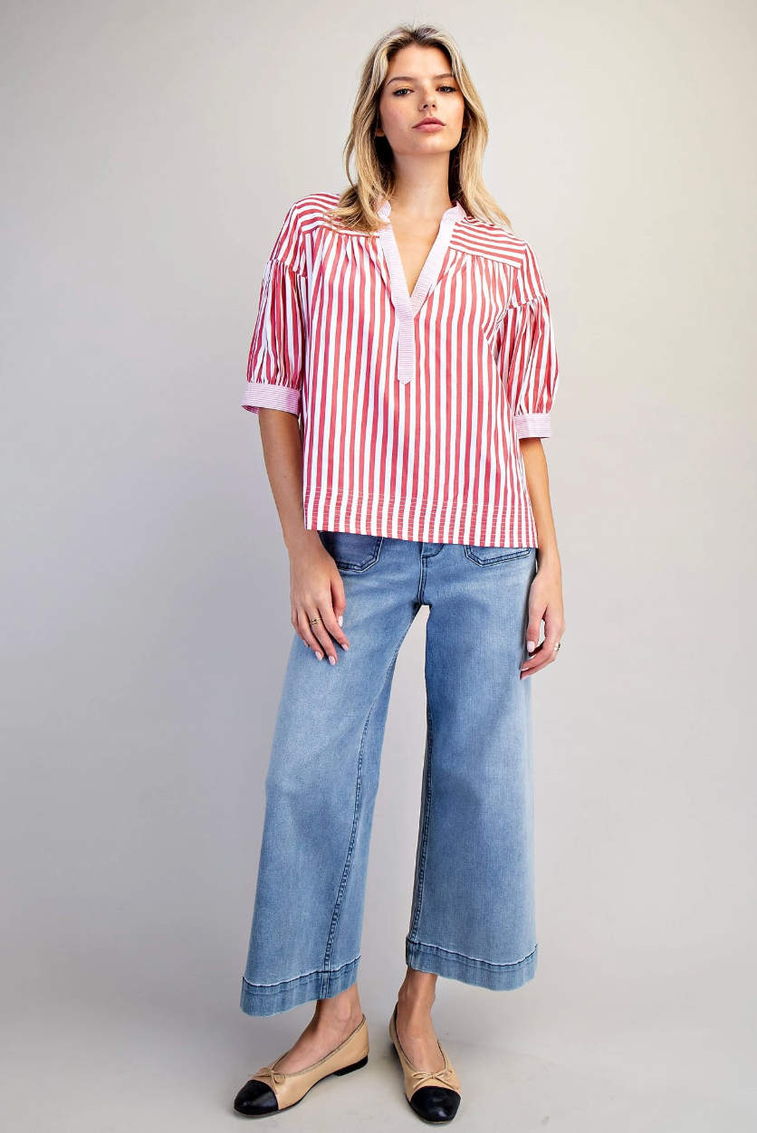 Woman wearing a red and white striped shirt and blue jeans on a gray background