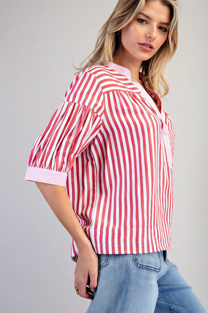 Woman wearing a red and white striped shirt with blue jeans on a gray background