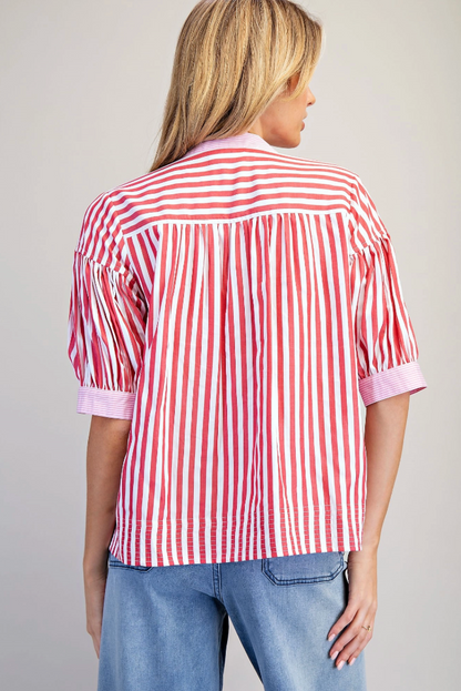 Person wearing a red and white striped shirt with rolled-up sleeves on a plain background