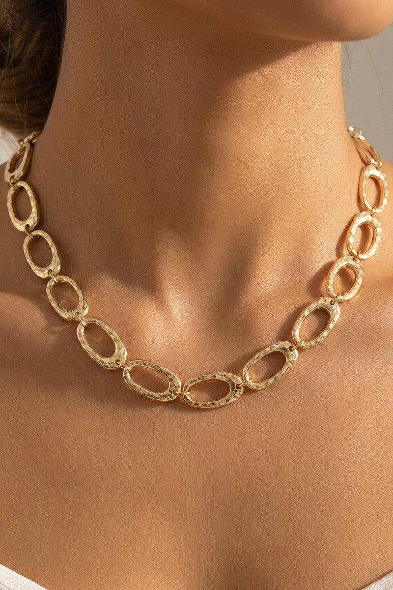 Gold chain necklace on a person against a neutral background