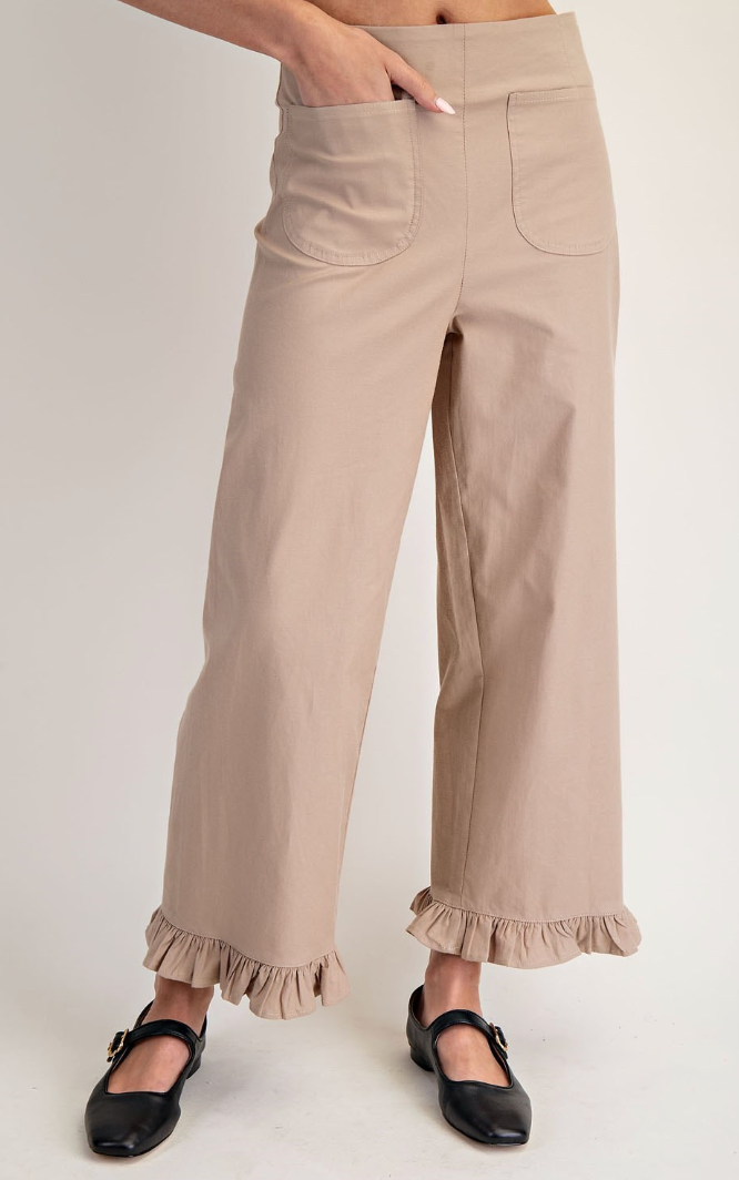 Beige pants with ruffled cuffs worn by a person on a white background