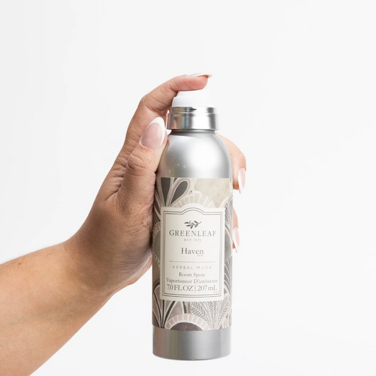 A hand holding a silver spray bottle of Greenleaf London Haven Herbal Mist against a clean white background.