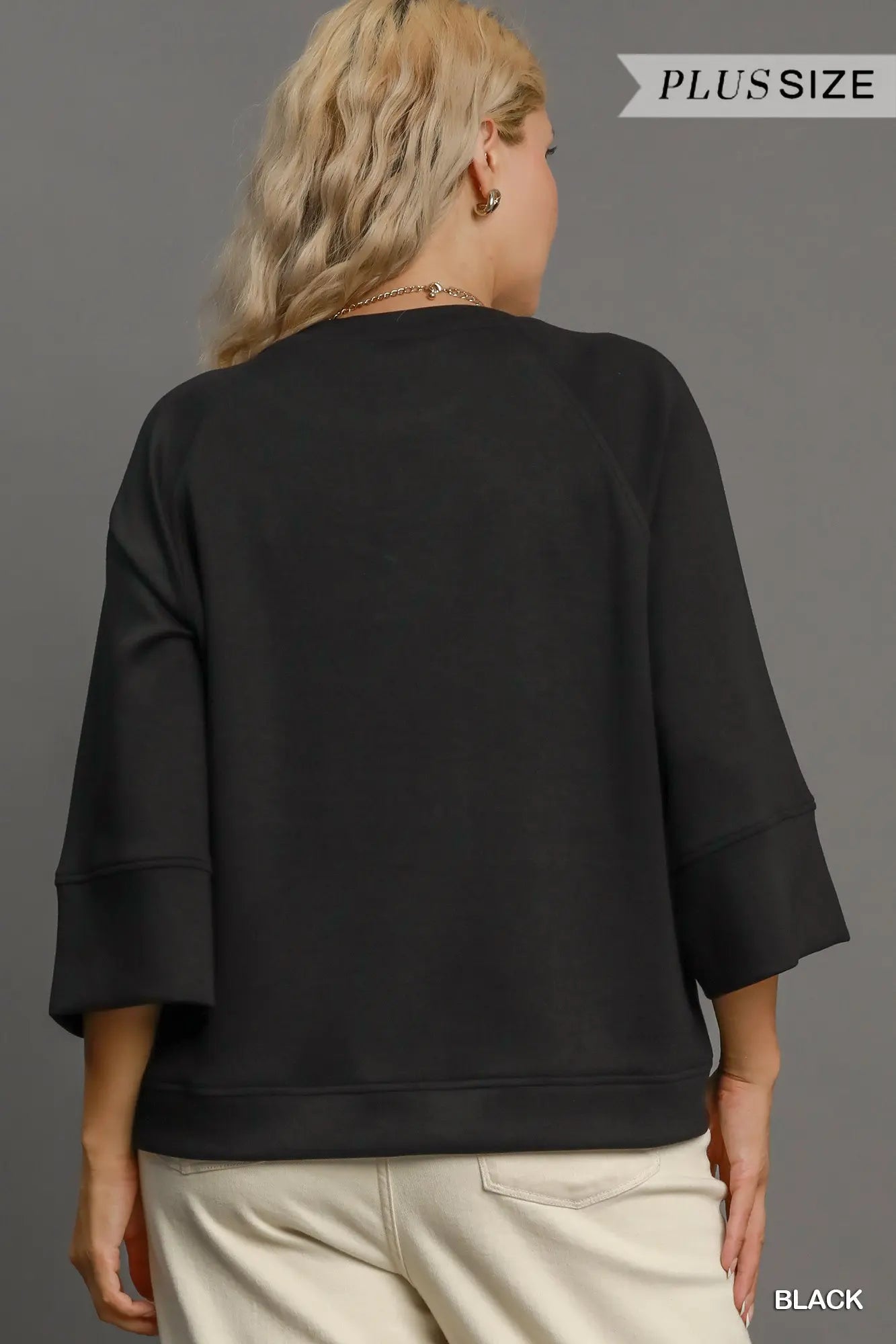 Person wearing a black plus-size sweatshirt on a gray background