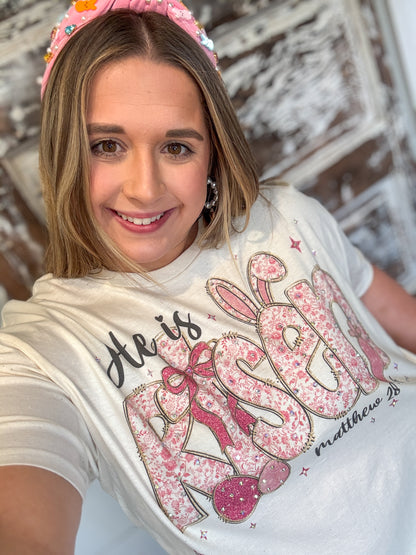Woman wearing a white t-shirt with pink text and graphics, smiling at the camera.