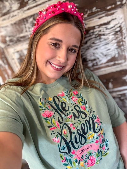 Woman wearing a green t-shirt with floral text design and a pink headband against a wooden background.