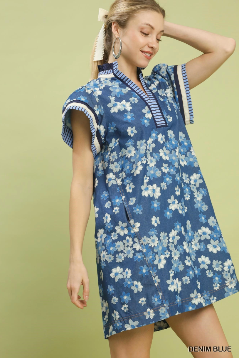 Woman wearing a denim blue floral dress against a green background