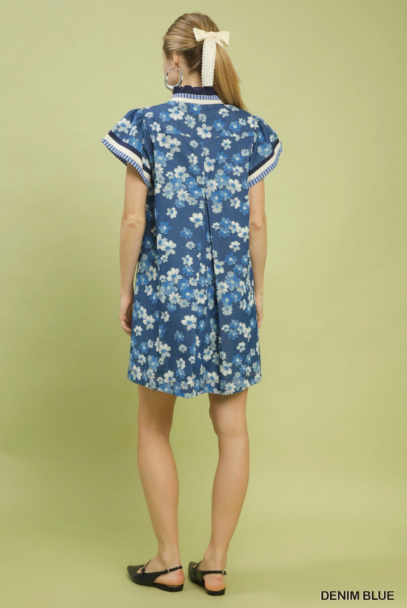 Woman wearing a denim blue floral dress against a light green background