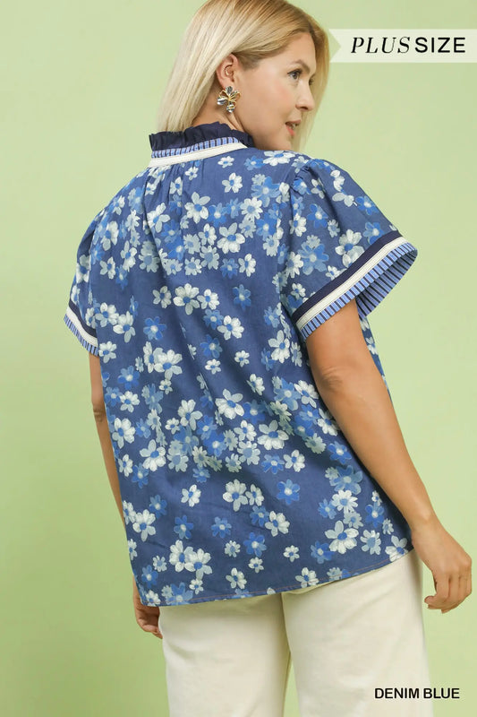 Woman wearing a blue floral blouse with white pants on a light green background