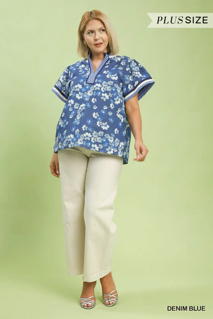 Woman wearing a blue floral blouse and white pants on a light green background