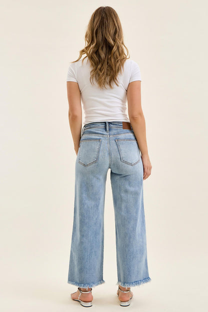 Person wearing light blue jeans and a white t-shirt on a plain background