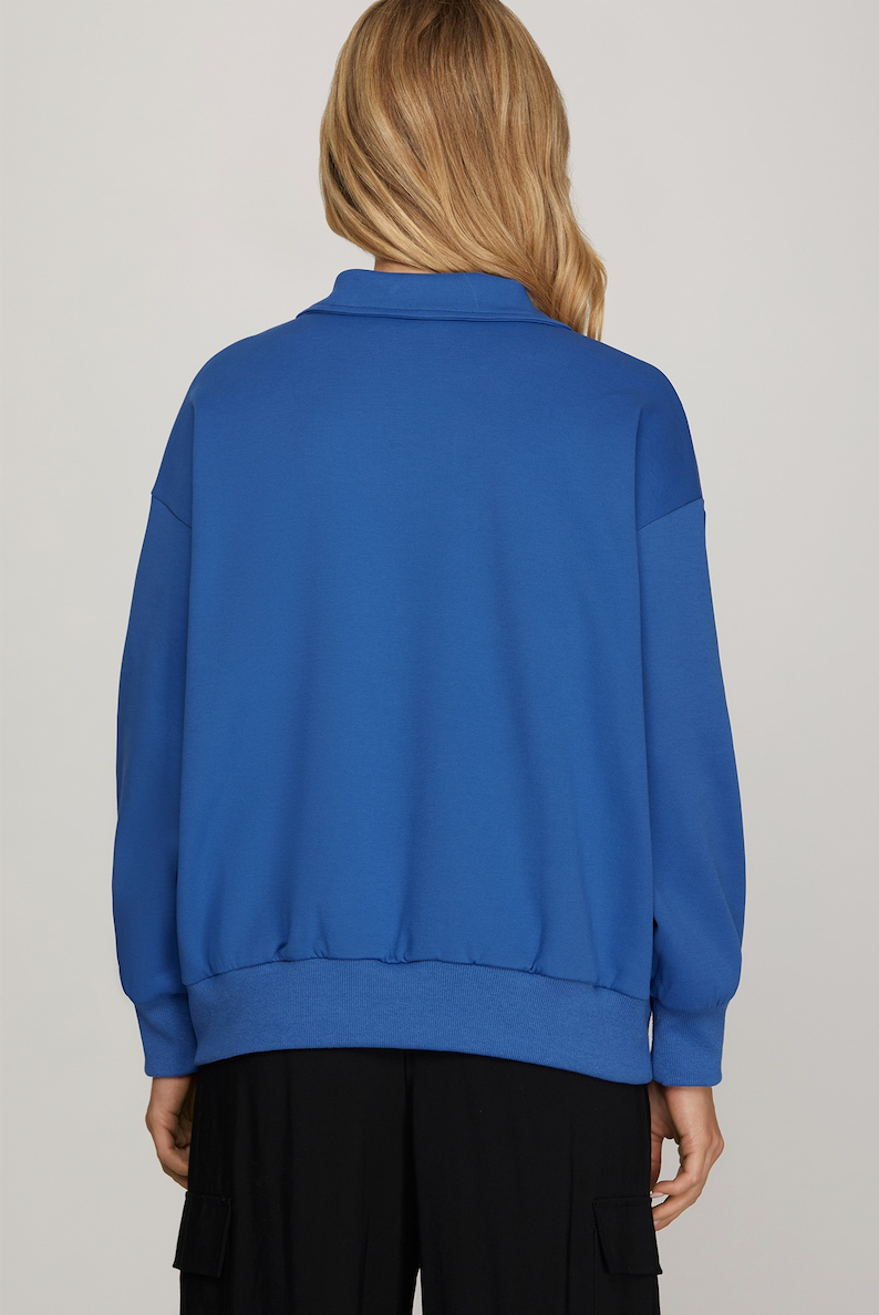 Blue sweatshirt worn by a person on a plain background