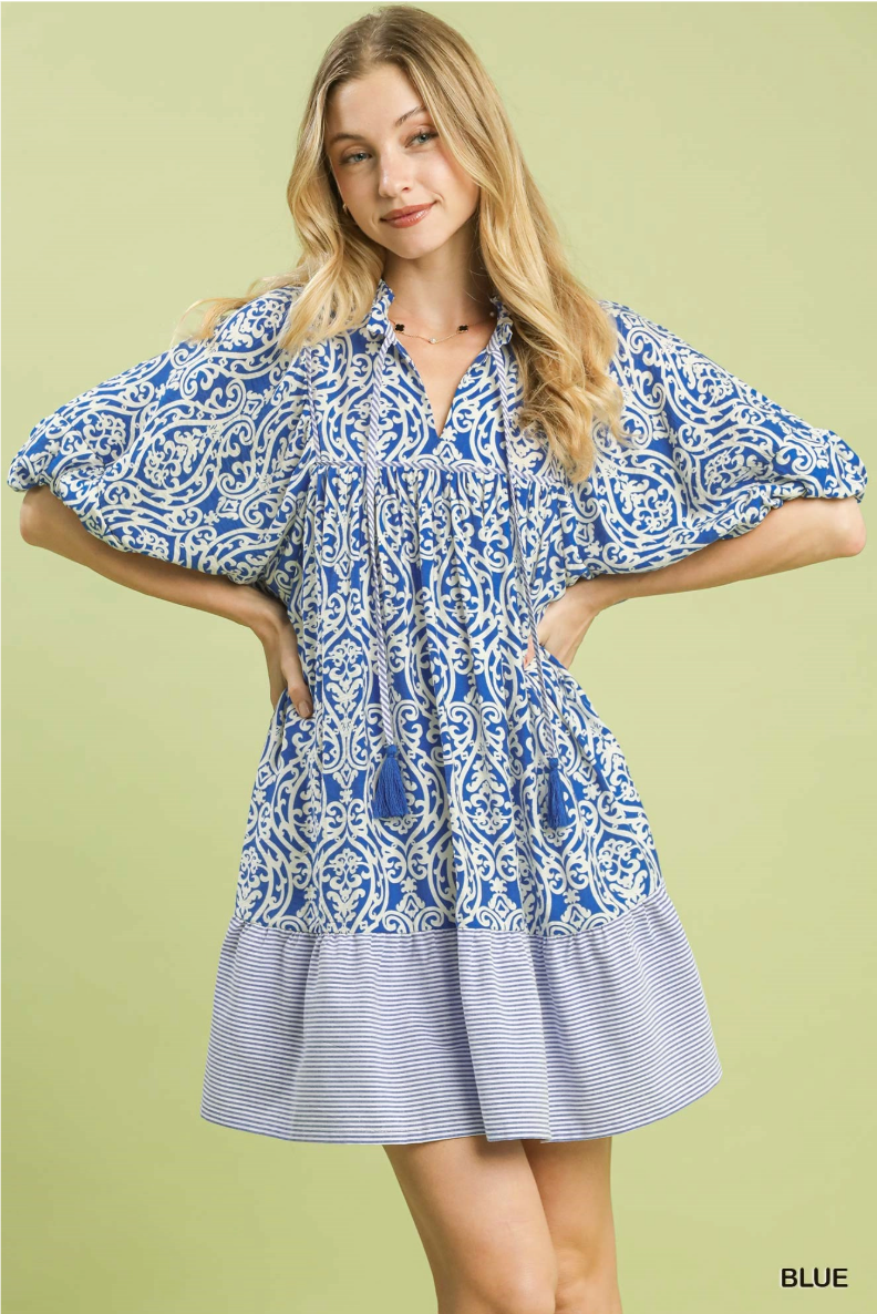Woman wearing a blue and white patterned dress on a green background