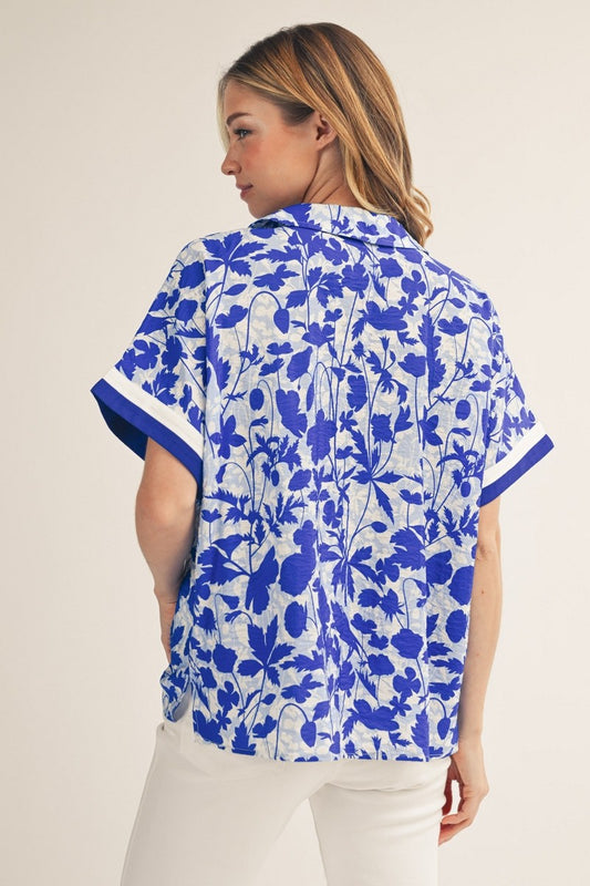 Woman wearing a blue floral patterned shirt against a beige background