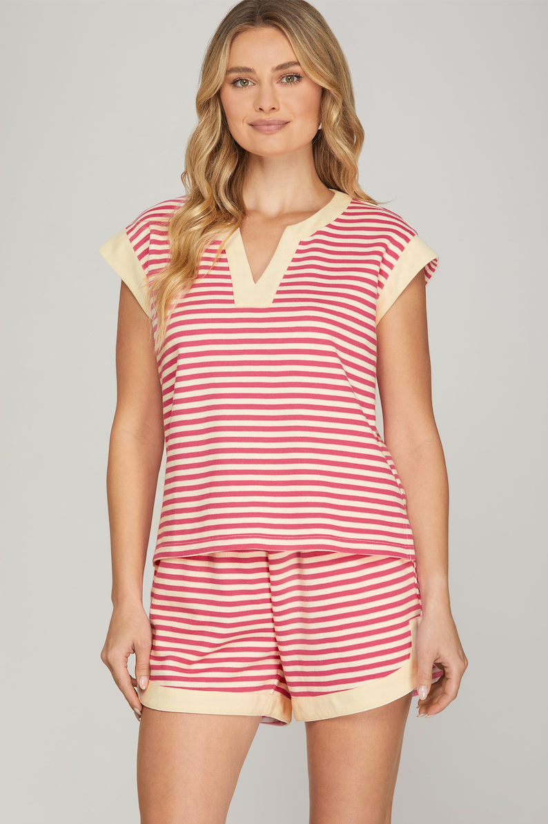 Woman wearing a red and white striped romper with beige trim on a gray background