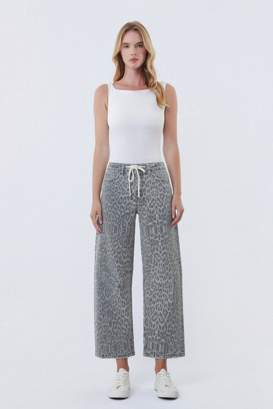 Woman wearing a white tank top and patterned pants on a white background