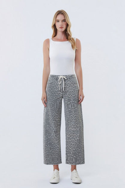 Woman wearing a white tank top and patterned pants on a white background