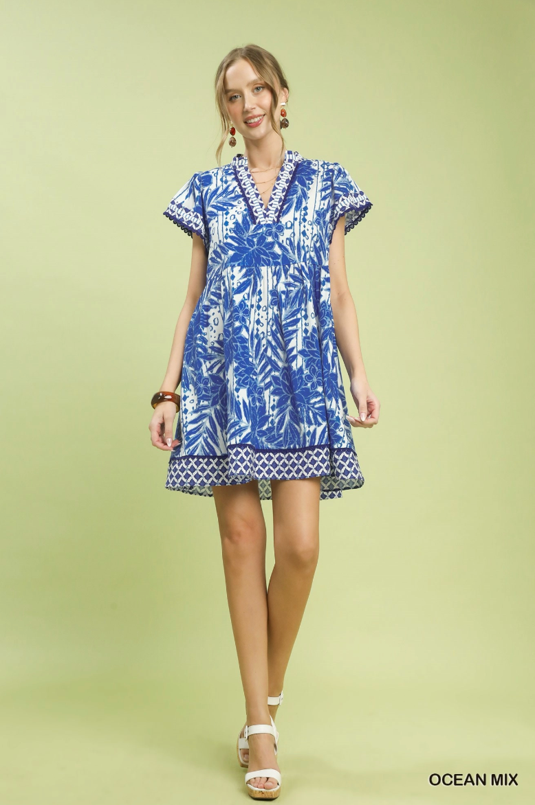 Woman wearing a blue and white patterned dress on a light green background