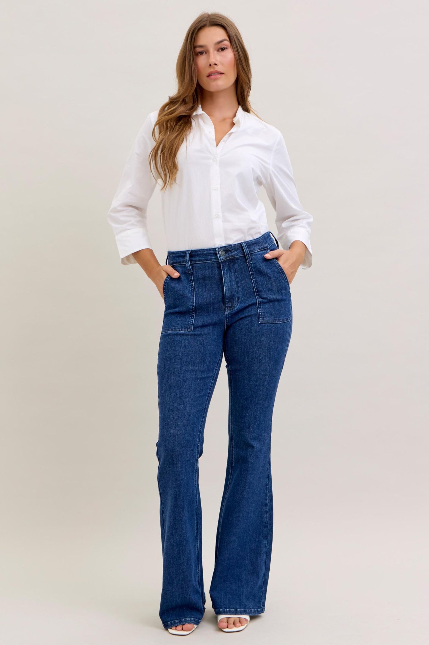 Woman wearing a white shirt and blue jeans on a plain background