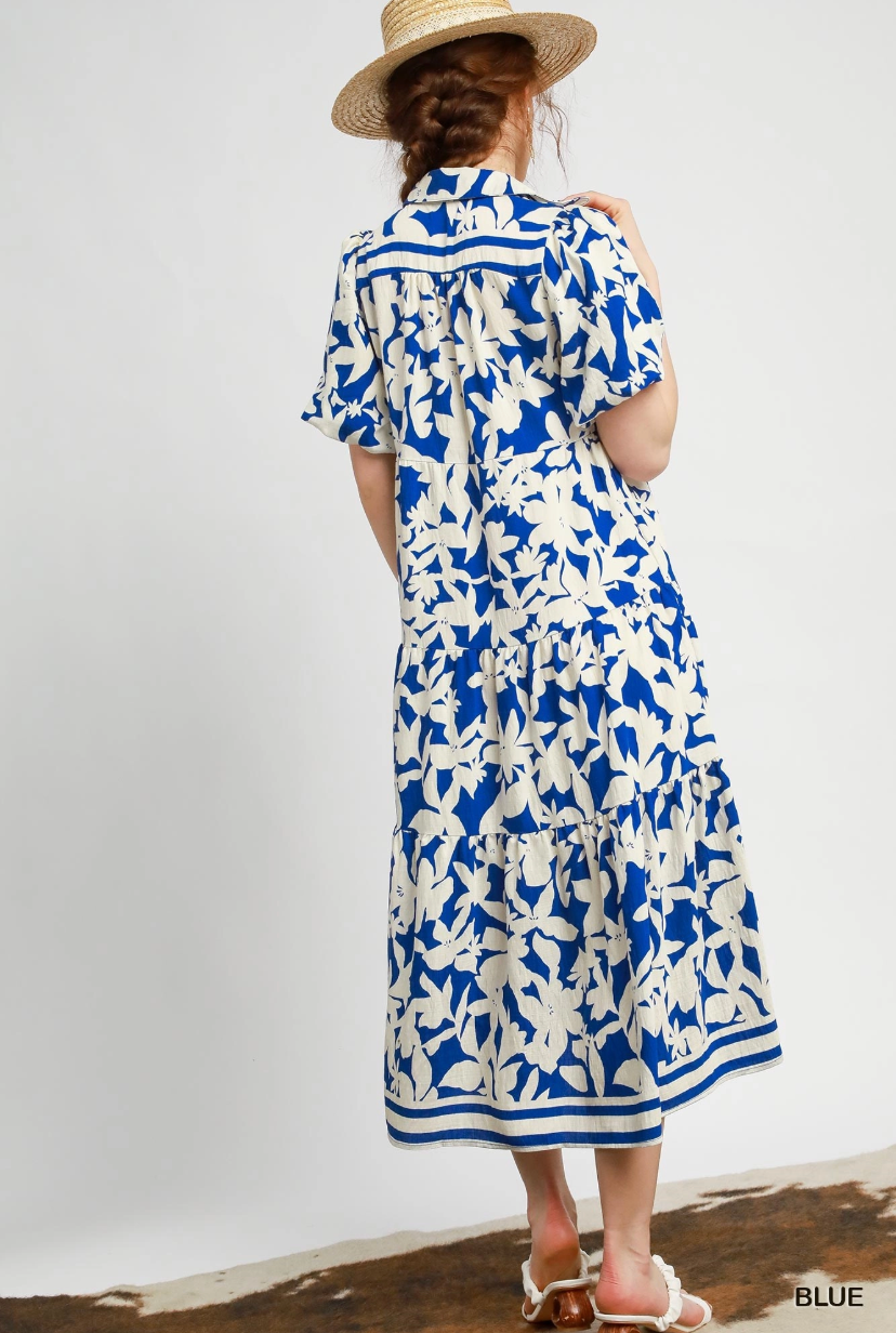 Woman wearing a blue and white floral dress with a straw hat on a plain background