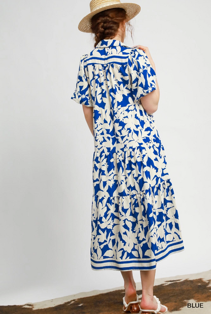 Woman wearing a blue and white floral dress with a straw hat on a plain background