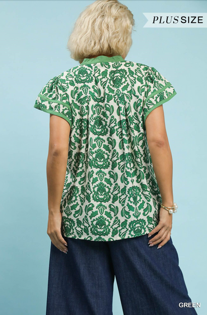 Woman wearing a green floral patterned blouse against a light blue background