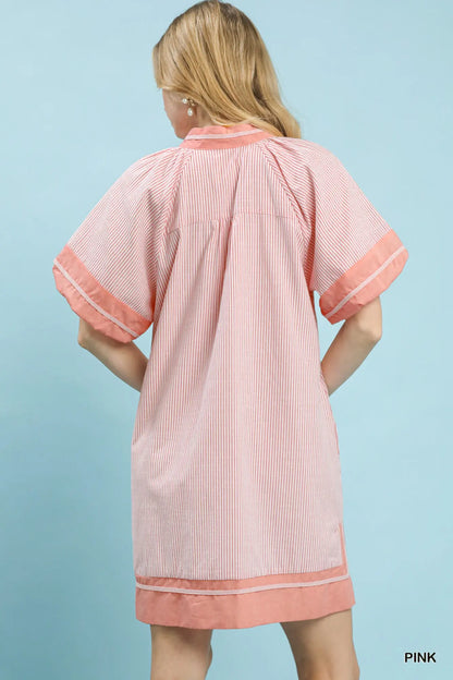 Woman wearing a pink and white striped dress against a light blue background