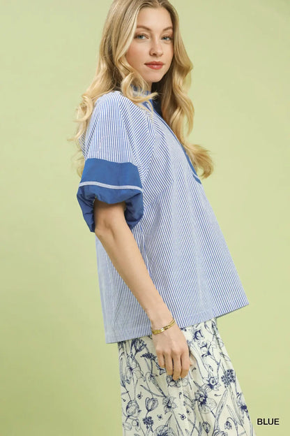 Woman wearing a blue and white striped shirt with floral pants on a light green background