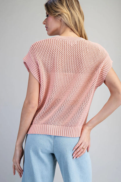 Woman wearing a pink knitted top against a gray background