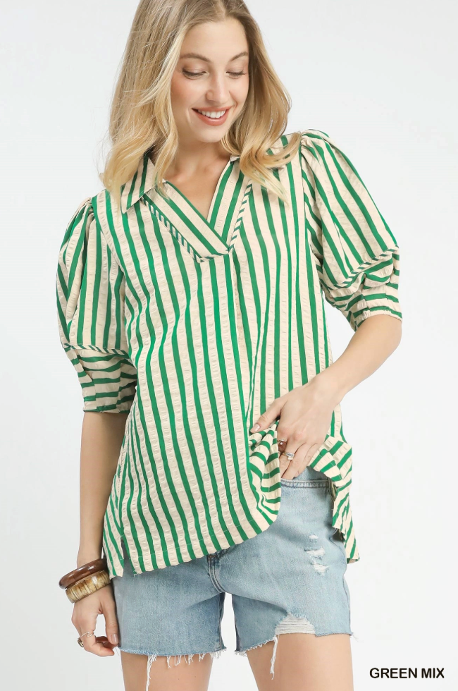 Woman wearing a green and white striped shirt with denim shorts on a white background