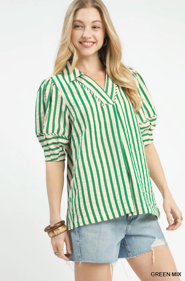 Woman wearing a green and white striped shirt with denim shorts on a white background
