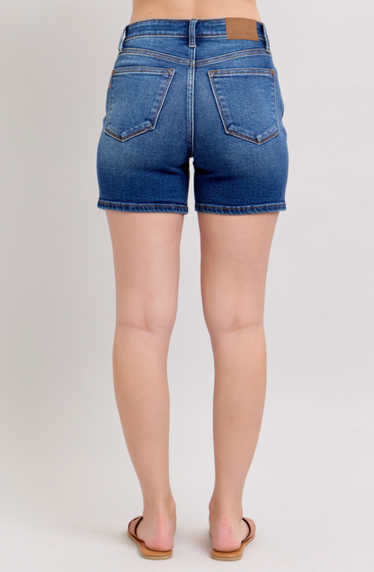 Person wearing blue denim shorts on a plain background