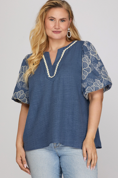 Woman wearing a blue blouse with floral patterns on a plain background