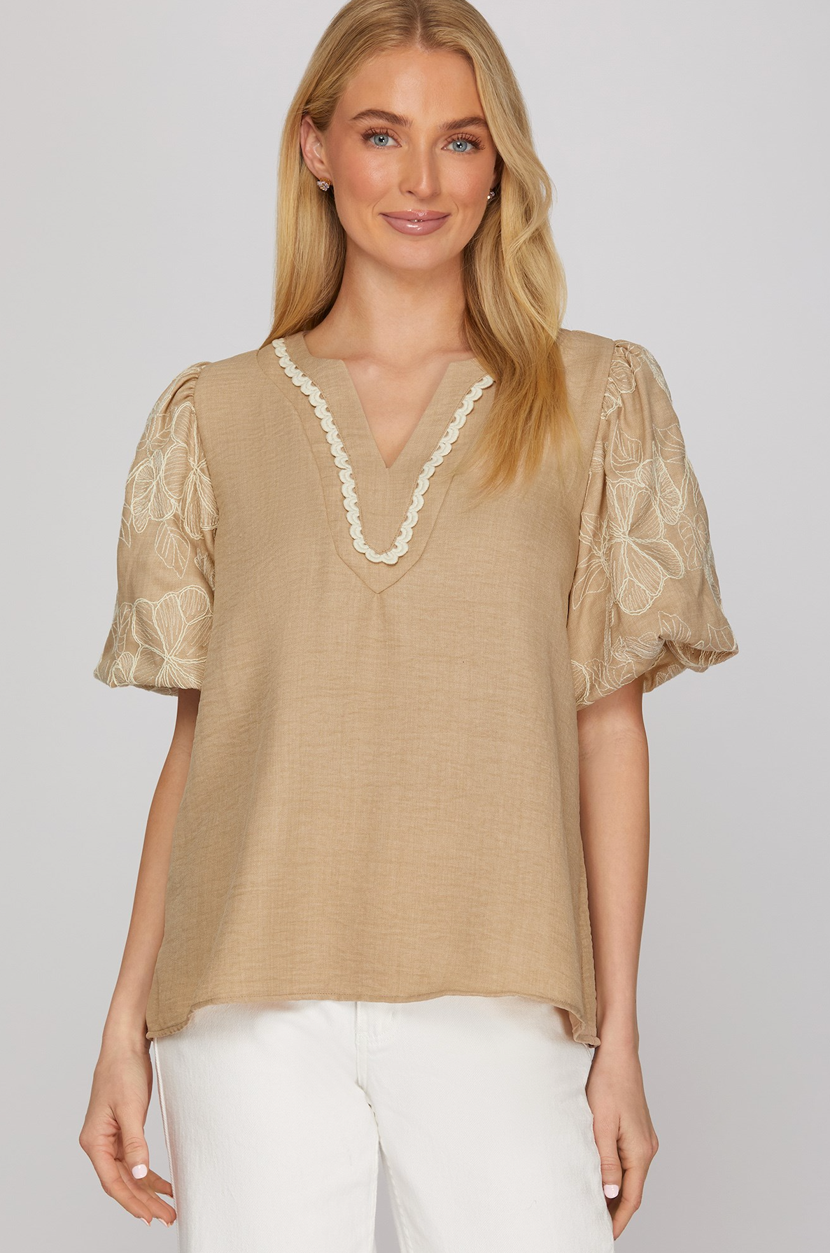 Woman wearing a beige blouse with lace details on a white background