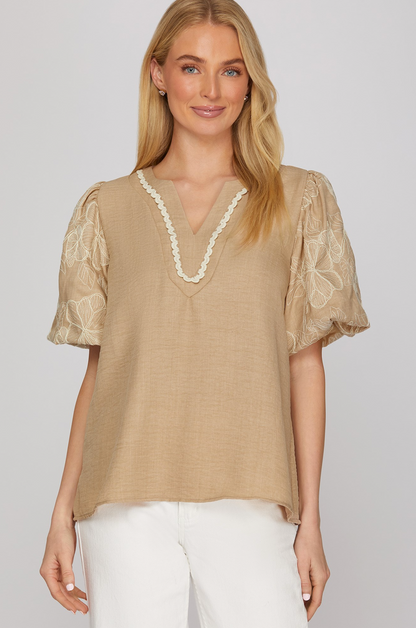 Woman wearing a beige blouse with lace details on a white background