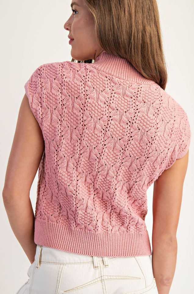 Pink knitted vest worn by a person on a white background