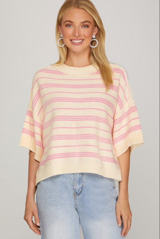 Woman wearing a striped sweater and jeans on a plain background