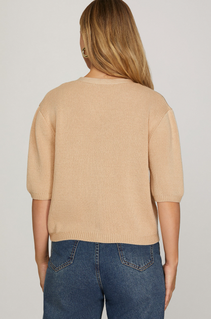 Person wearing a beige sweater and blue jeans on a plain background