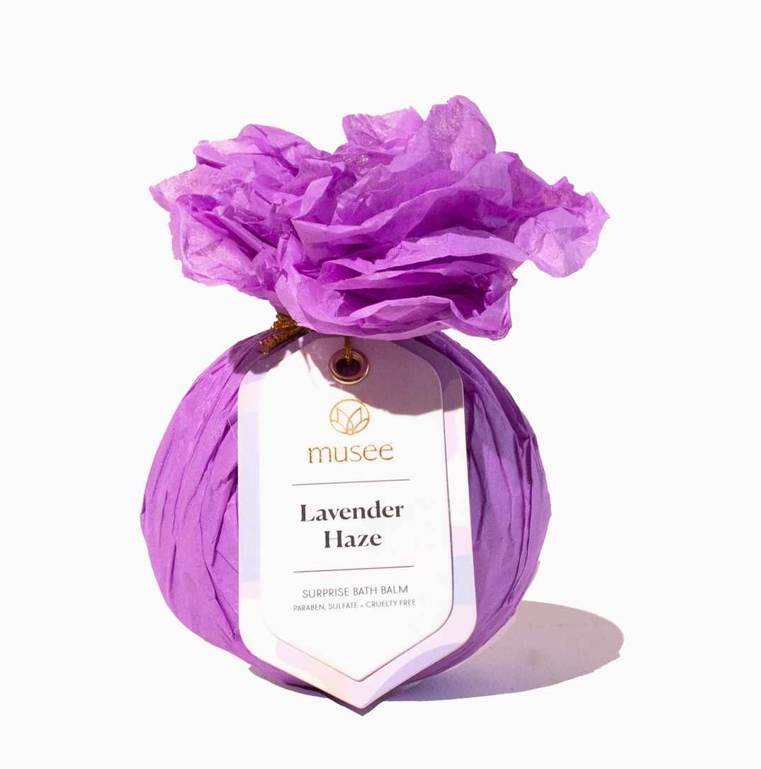 Purple bath balm with a flower on top labeled 'musee Lavender Haze' against a white background